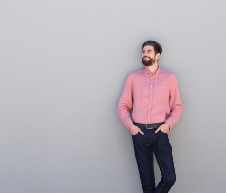 Side portrait of happy man standing against gray wall looking away