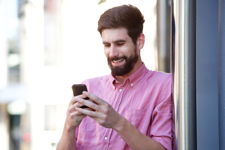 Portrait of happy businessman outside in city looking at cellphoneの写真素材