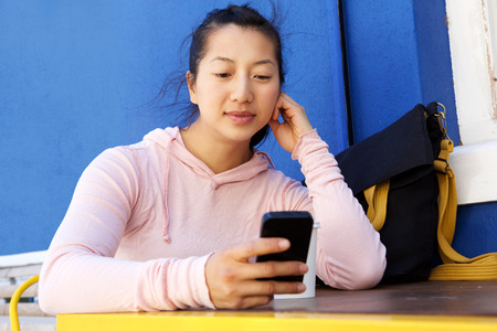 Close up portrait of asian woman sitting at cafe using mobile phone