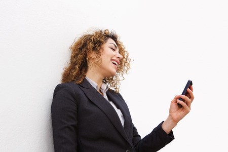 Portrait of smiling young business woman looking at mobile phoneの写真素材