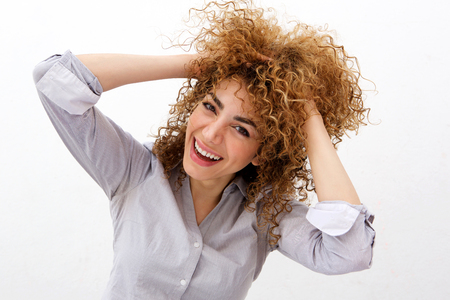Portrait of happy young woman laughing with hand in hair against white backgroundの写真素材