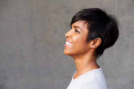 Side portrait of beautiful young african woman looking happy against gray backgroundの写真素材