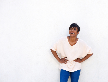 Portrait of young african american lady laughing against white wall with copy spaceの写真素材