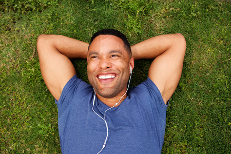 Top view portrait of happy young african man lying on grass with earphones
の写真素材