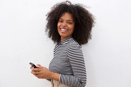 Portrait of happy woman with curly hair holding mobile phoneの写真素材