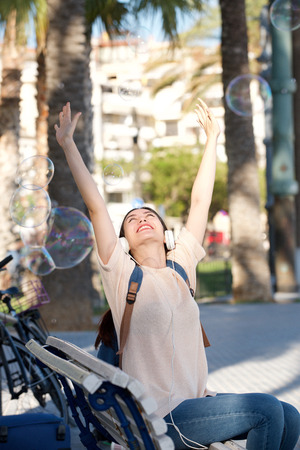 Portrait of happy young woman with headphones and arms outstretchedの写真素材