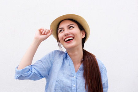 Close up portrait of fashionable young woman smiling with hand to hatの写真素材