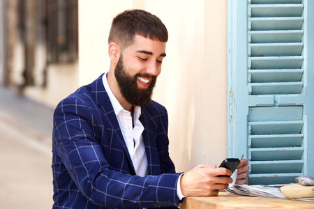 Portrait of smiling man in business suit sitting with mobile phoneの写真素材