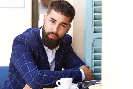 Close up portrait of serious businessman sitting outside with coffeeの写真素材