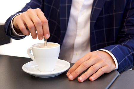 Close up portrait of businessman stirring hot coffee at cafeの写真素材