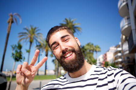 Portrait of happy man taking selfie by palm treesの写真素材