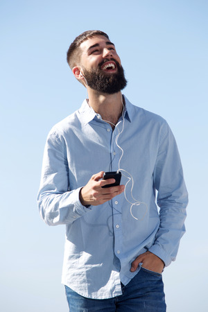 Portrait of laughing man with mobile phone listening to musicの写真素材