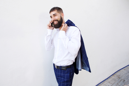 Portrait of happy businessman walking and talking on smart phoneの写真素材