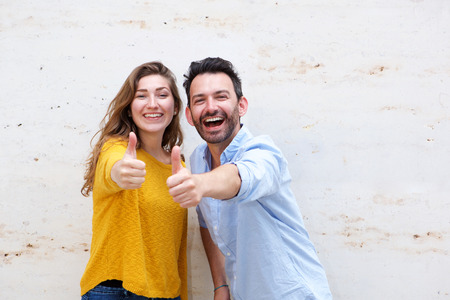 Portrait of happy couple standing with two thumbs upの写真素材
