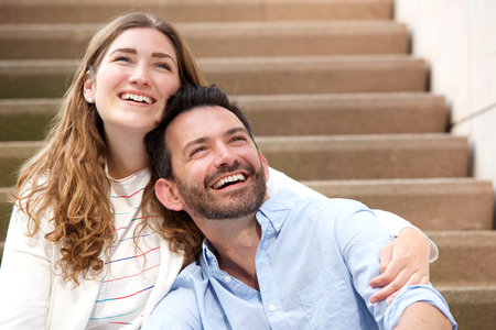 Close up portrait of happy couple sitting together on staircase in embraceの写真素材