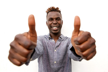 Close up portrait of smiling young afro man with two thumbs up on white backgroundの写真素材