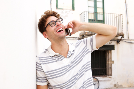 Side portrait of laughing man talking on smart phone on city streetの写真素材