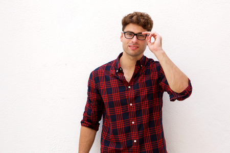 Portrait of smiling handsome man thinking with hand to glassesの写真素材