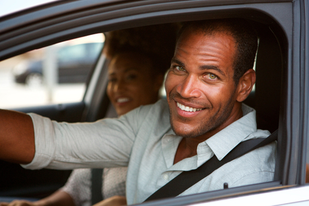 Close up portrait of cheerful man and woman in car on road trip