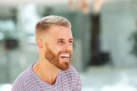 Close up portrait of young man with beard laughingの写真素材