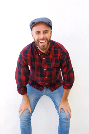 Portrait of happy young man laughing with hands on kneesの写真素材