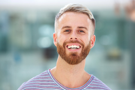 Close up portrait of handsome young man with beard laughingの写真素材