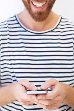 Close up portrait of smiling man in striped shirt holding mobile phoneの写真素材
