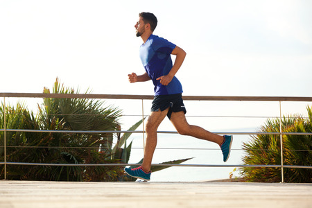 Full length profile portrait of young man running outside