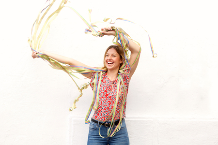 Portrait of young woman laughing with confetti against white backgroundの写真素材