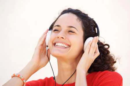 Close up portrait of attractive  young woman smiling and listening too music with headphones の写真素材