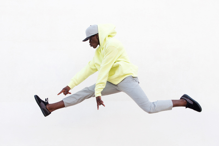 Portrait of young african man dancer doing leg split in mid air over white backgroundの写真素材