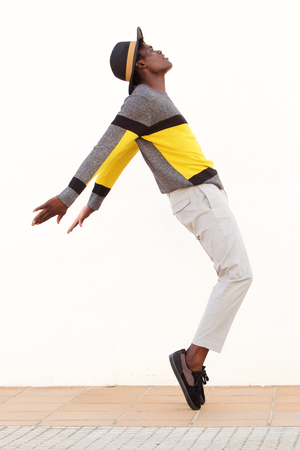 Full length side portrait of african male dancer standing on his tip toes making a cool dance poseの写真素材