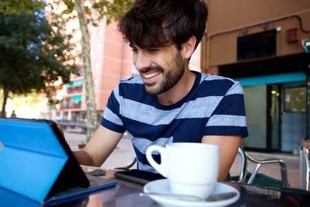 Portrait of happy man using digital tablet at outdoor cafeの写真素材