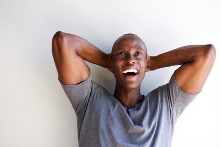 Close up portrait of african american laughing with hands behind head and looking up の写真素材