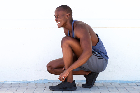 Side portrait of smiling sports man tying shoelace の写真素材