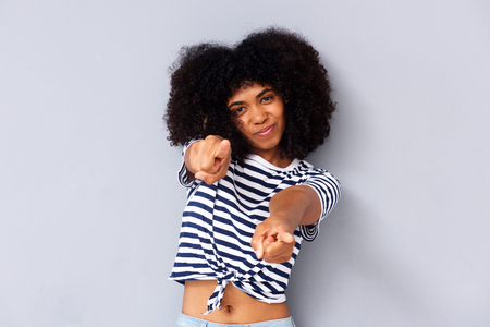 Portrait of cool young black woman pointing fingers on gray backgroundの写真素材