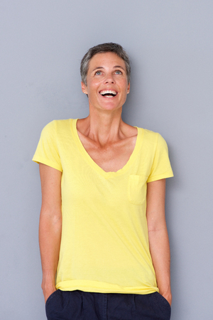 Portrait of happy older woman laughing by gray wallの写真素材