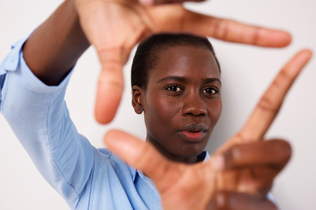 Close up portrait of young black woman making picture frame with fingersの写真素材