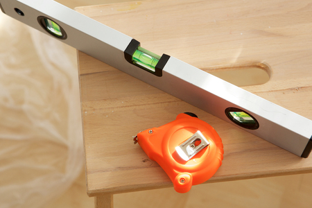Close up portrait of measuring tape and spirit level on wooden table