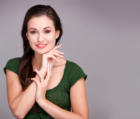 Close up portrait of beautiful young woman smiling against gray wallの写真素材