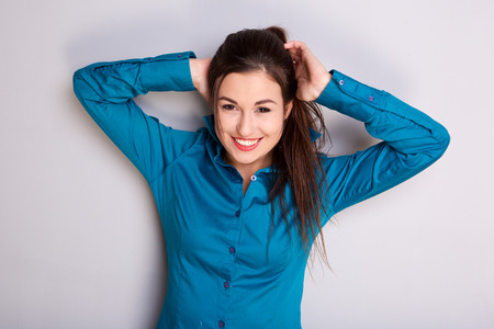 Portrait of attractive girl smiling hands in hair against gray backgroundの写真素材