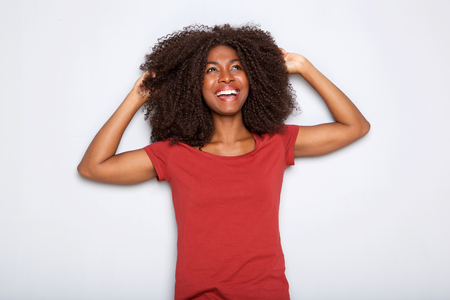 Portrait of happy young african american woman smiling with hands in hair on white backgroundの写真素材