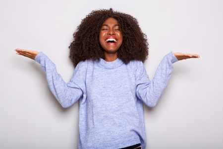Portrait of smiling young african woman feeling with spread palms against white backgroundの写真素材