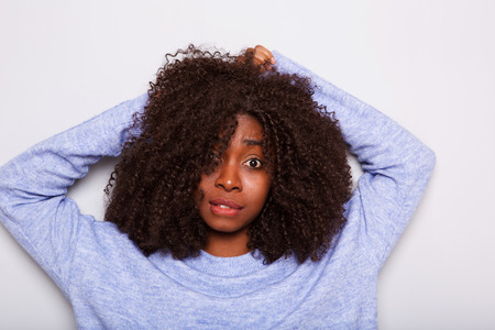 Portrait of young african american woman with curly hair looking surprised on white background