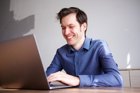 Close up portrait of smiling business man working from home on laptopの写真素材