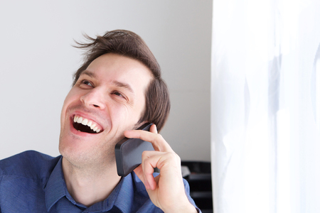 Close up portrait of handsome businessman on phone call laughingの写真素材