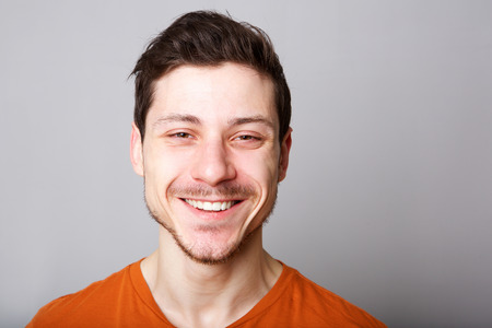 Close up horizontal portrait of smiling young man against gray backgorundの写真素材