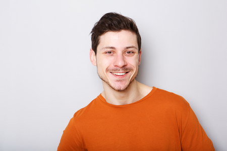 Close up portrait of smiling young man against gray backgroundの写真素材