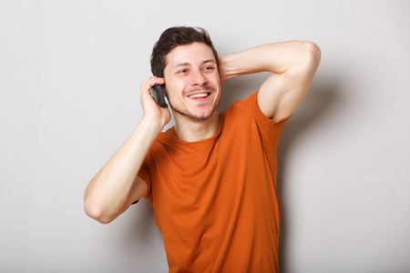 Portrait of happy young man talking on cellphone against gray backgroundの写真素材