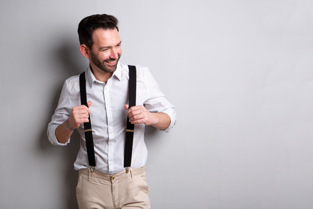 Portrait of middle age man with suspenders smiling against gray background の写真素材